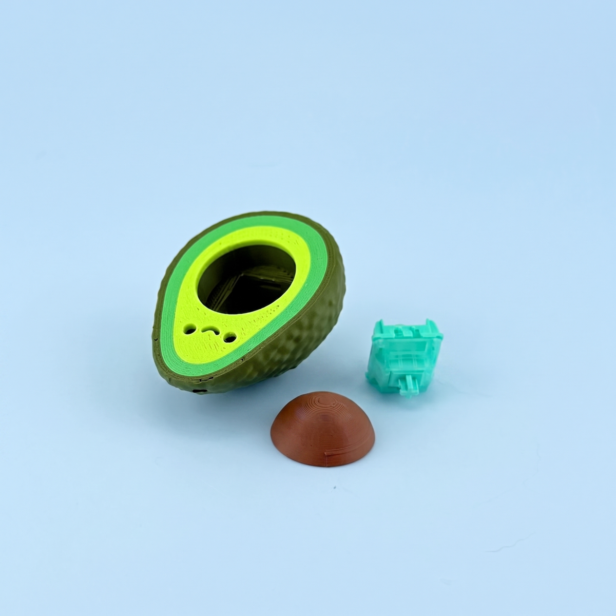 Avocado clicker parts laid out - printed shell, stone and the mechanical switch inside