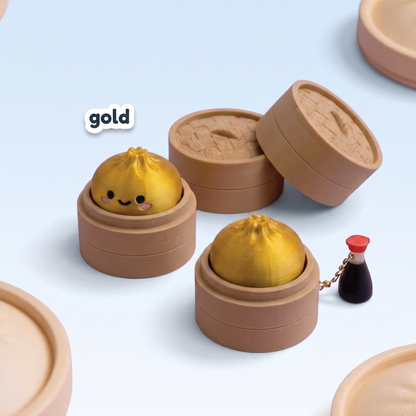 Metallic gold Dumpling Fidget Clicker keychain in its steamer basket