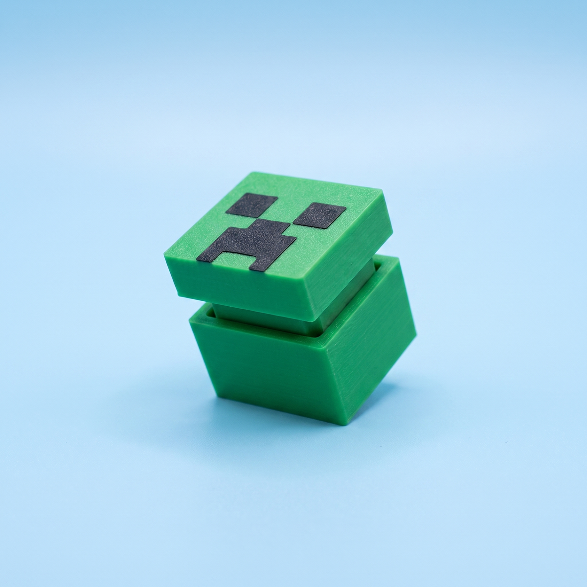 Green creeper-face fidget clicker with its lid pressed open
