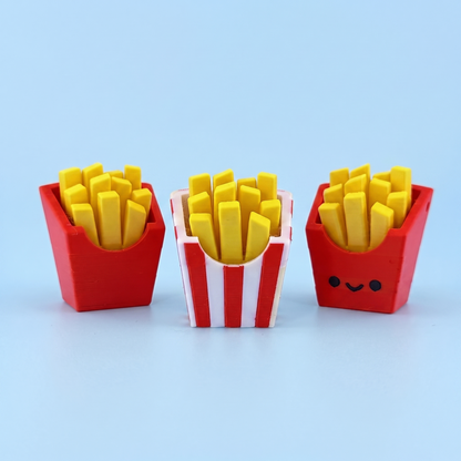 Three 3D printed french fries fidget clickers in plain red and striped cartons