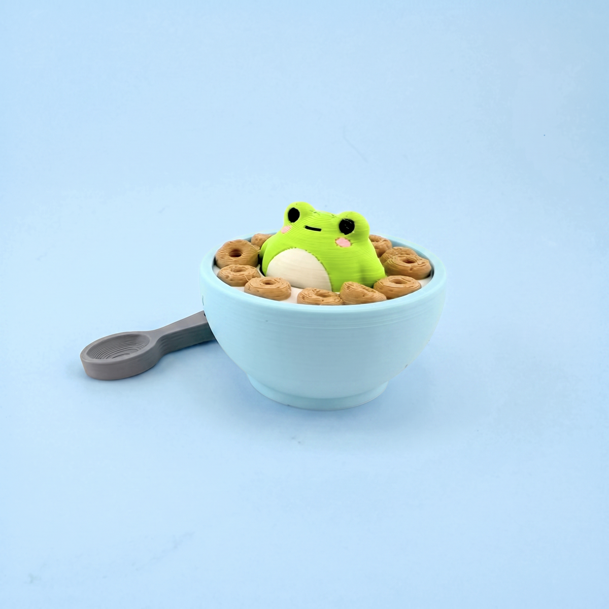 Frog-in-the-milk cereal bowl fidget clicker in a light blue bowl